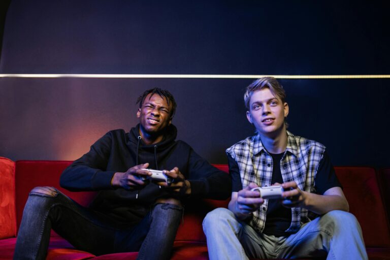 Two young men enjoying video games together on a couch, capturing leisure and friendship.